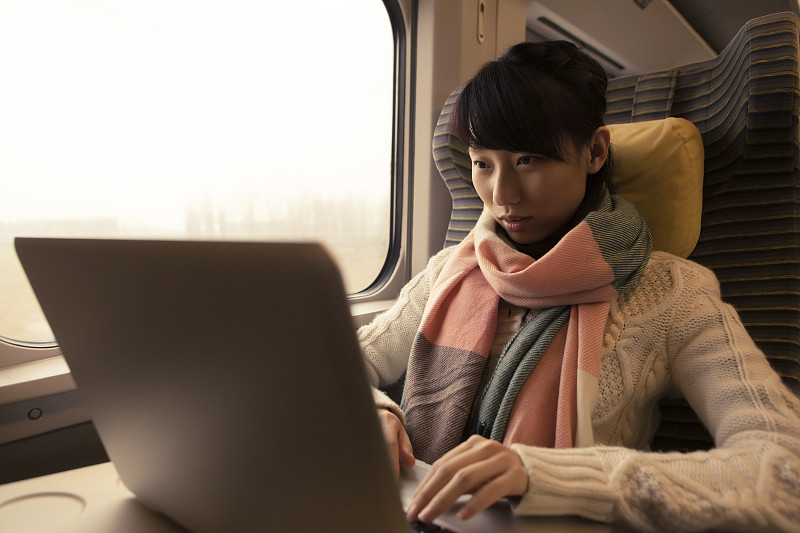年轻女子在乘火车旅行时使用电脑图片下载
