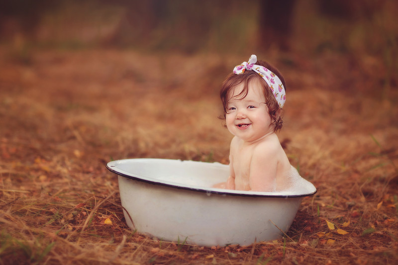 快乐的小女孩坐在外面的洗脸盆里图片下载