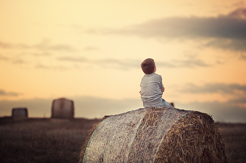 日落时分，男孩坐在干草捆上图片素材