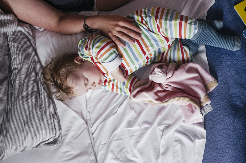 裁剪图像的妇女触摸女婴在床上图片下载