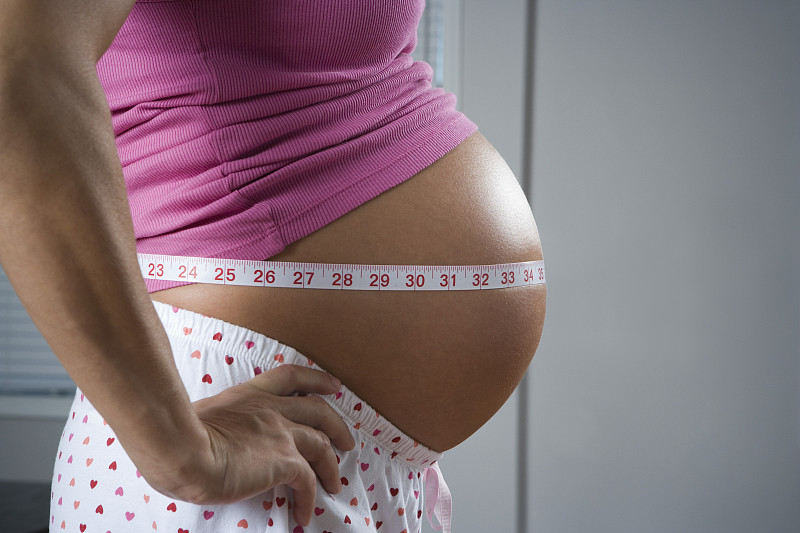 一个孕妇的侧面用卷尺绕着她的肚子图片下载