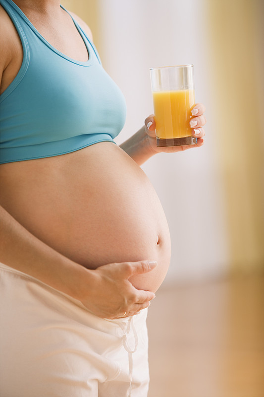 孕妇抱着肚子喝着果汁图片下载
