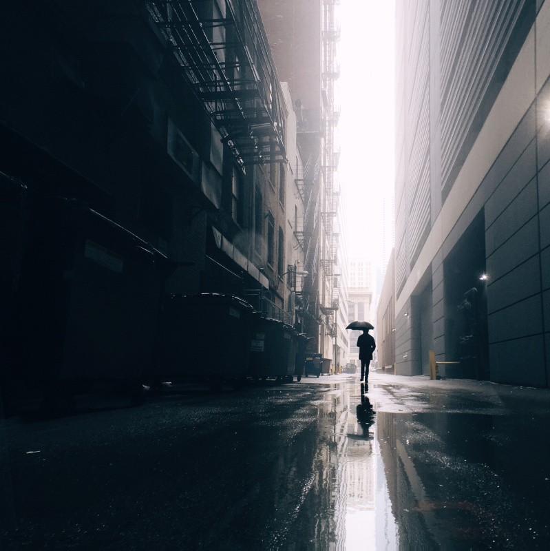 带着雨伞的男人走在城市街道上图片素材