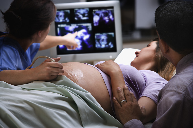女医生指着超声波照片，上面有个孕妇摄影图片下载