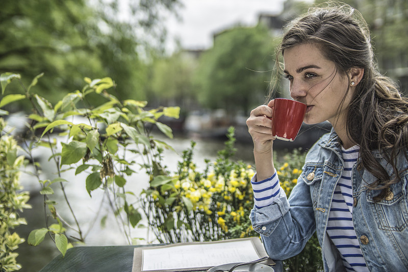 荷兰，阿姆斯特丹，一名女子在街头咖啡馆喝咖啡图片下载