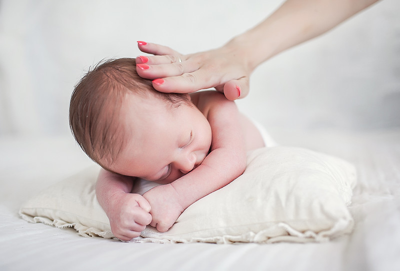 熟睡的新生男婴和母亲的爱抚图片下载