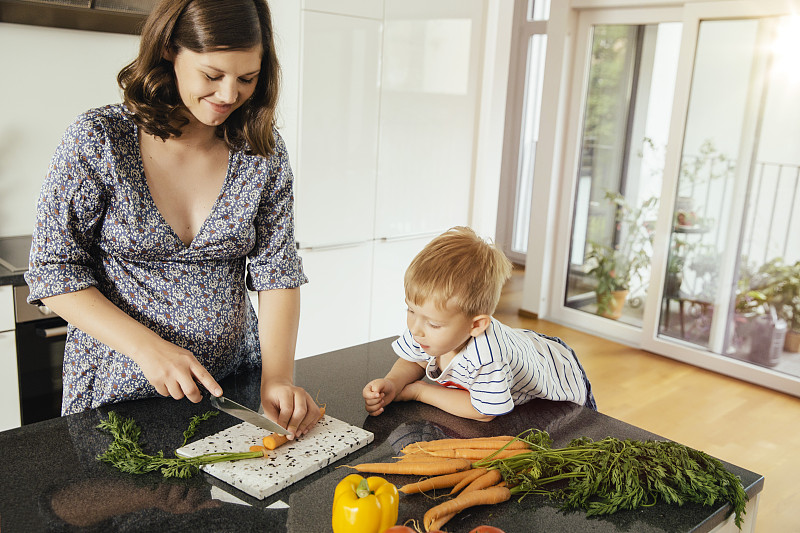 一个孕妇和她的儿子在厨房切菜图片下载
