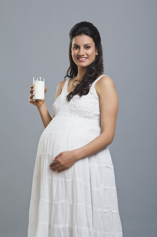 一个孕妇拿着一杯牛奶的肖像图片下载
