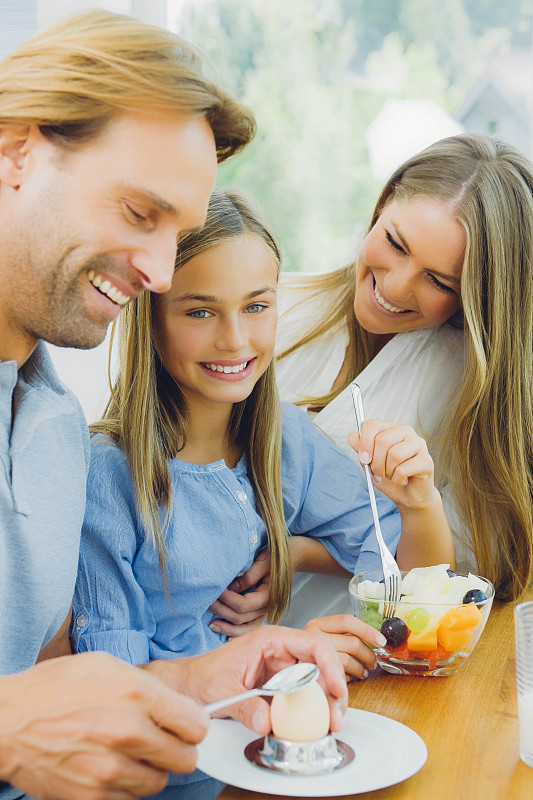 快乐的妈妈，爸爸和女儿在餐桌上吃饭图片下载