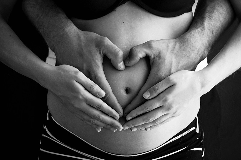 手在怀孕的肚子上呈心形图片下载