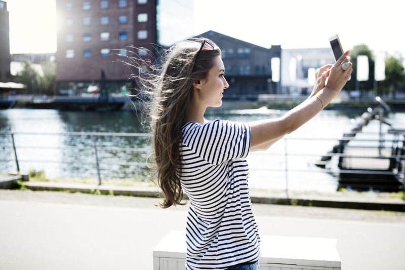 德国杜伊斯堡，一名年轻女子在用智能手机自拍图片素材