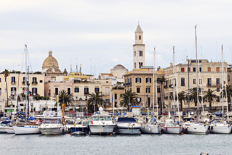 意大利，阿普利亚，巴里，码头上的船只和城市建筑的背景图片素材