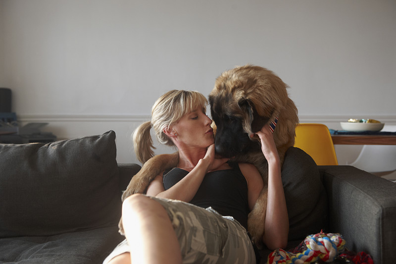 一个白人女人在沙发上亲吻一只狗图片下载