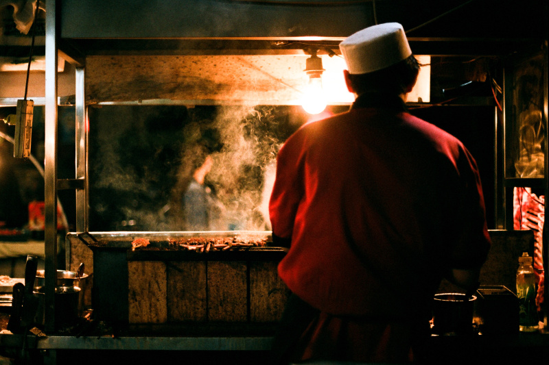 男人在街市档位烹煮食物的后视图图片素材