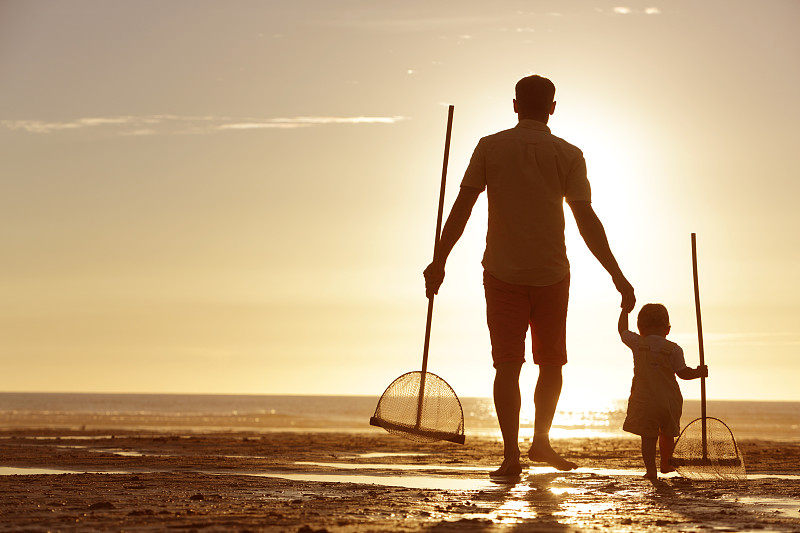 日落时分，父亲和女儿在海滩上散步图片下载