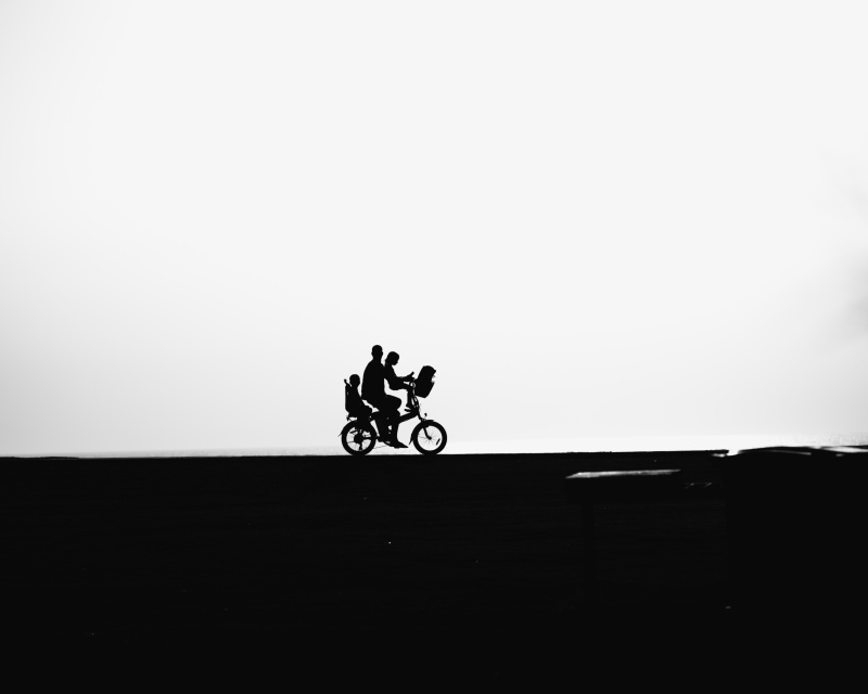 父亲和儿子、女儿在天空下的街道上骑自行车图片素材