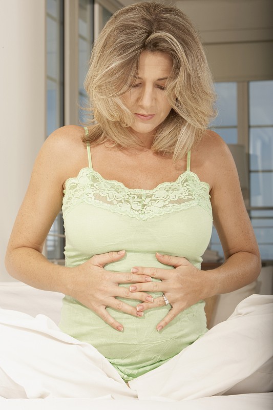 怀孕的中年妇女触摸她的腹部图片下载