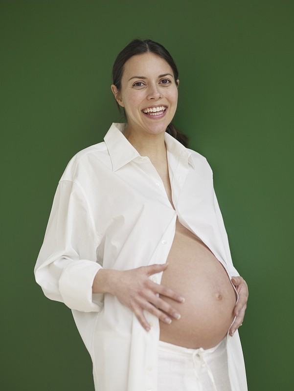 孕妇抱着裸露的腹部，微笑着图片下载