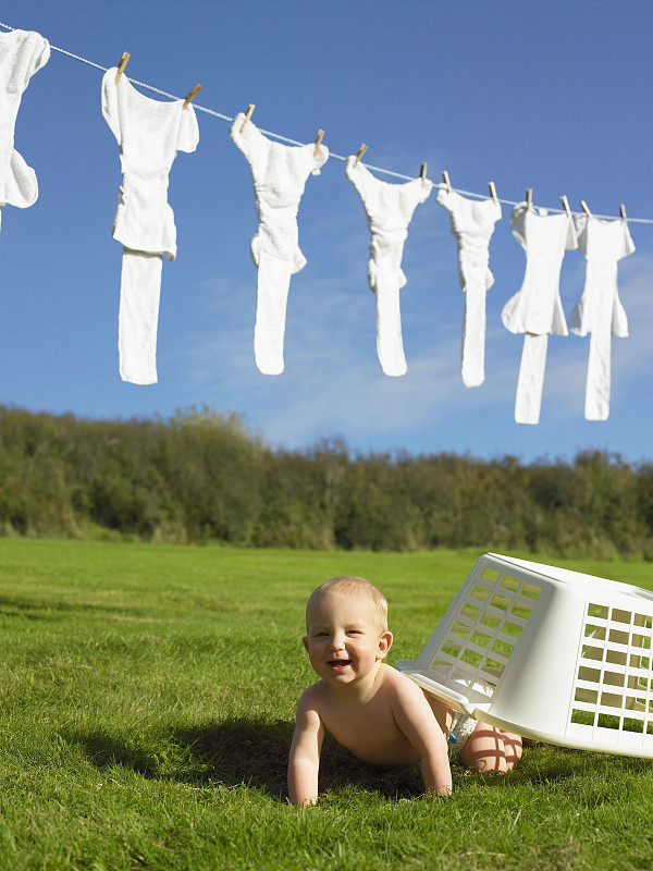 婴儿爬着洗衣篮。图片下载