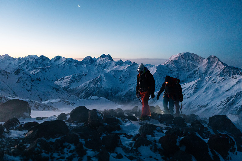 登山运动员在日出时登上积雪的山脊图片下载