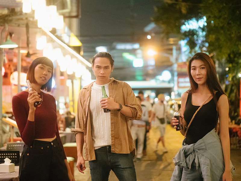 亚洲男子游客喝啤酒与他的朋友在街头小吃柜台晚上图片下载