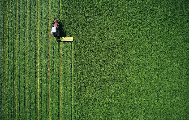拖拉机在绿色的田野上对称地耕作图片下载