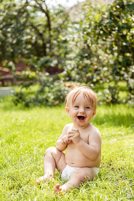 小男孩坐在草地上笑图片素材