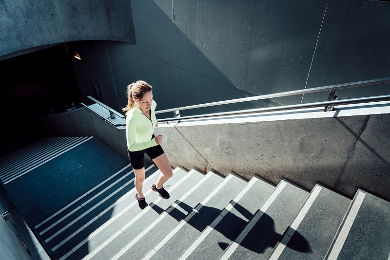 年轻的运动型女人跑上楼梯图片素材