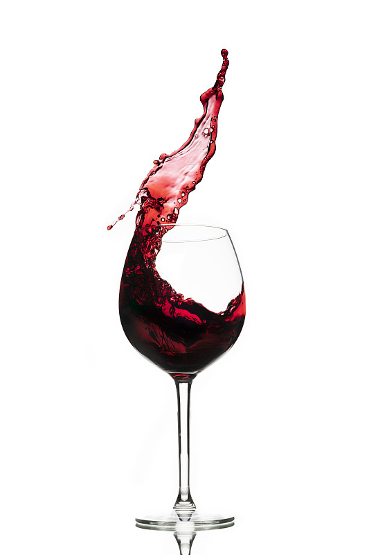 在白色背景下，红酒在玻璃杯中溅起。副本的空间。图片素材