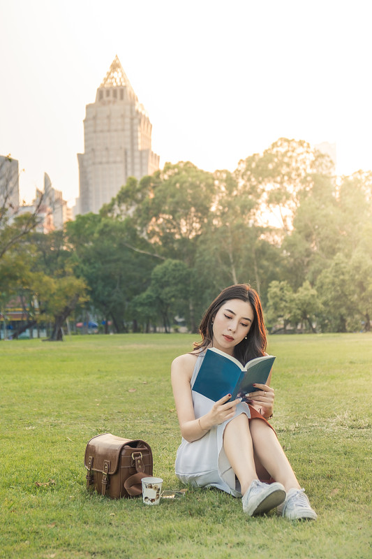 年轻女子在城市公园里放松地看书图片下载