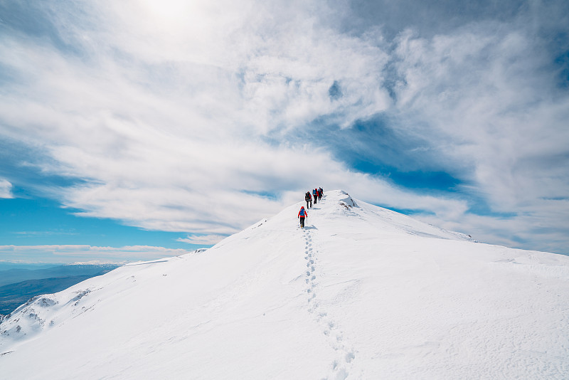 冬季高山登山队在高海拔的山峰上连续向上攀登图片素材