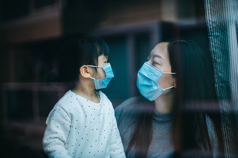 新冠肺炎疫情爆发，年轻的母亲和小女儿戴着防护口罩，在家中自我隔离，以保护和防止病毒传播图片下载