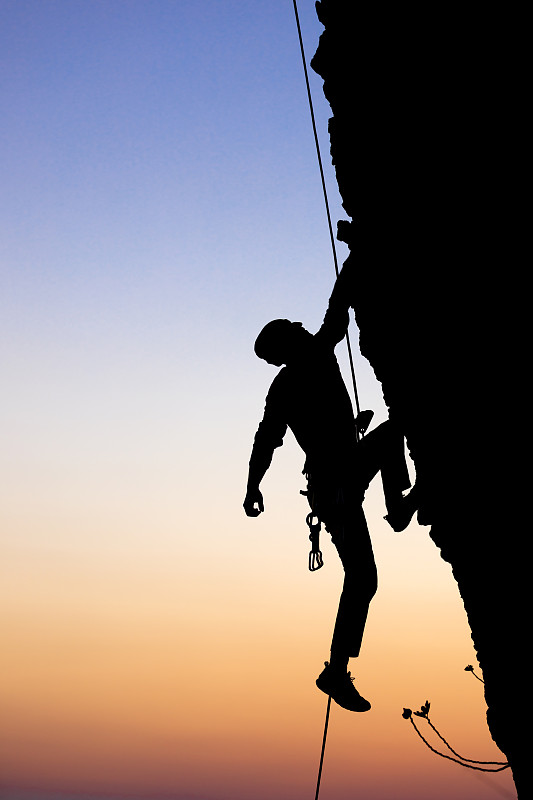 男性攀岩者向上拉，做下一步到达顶端。侧视图。图片素材
