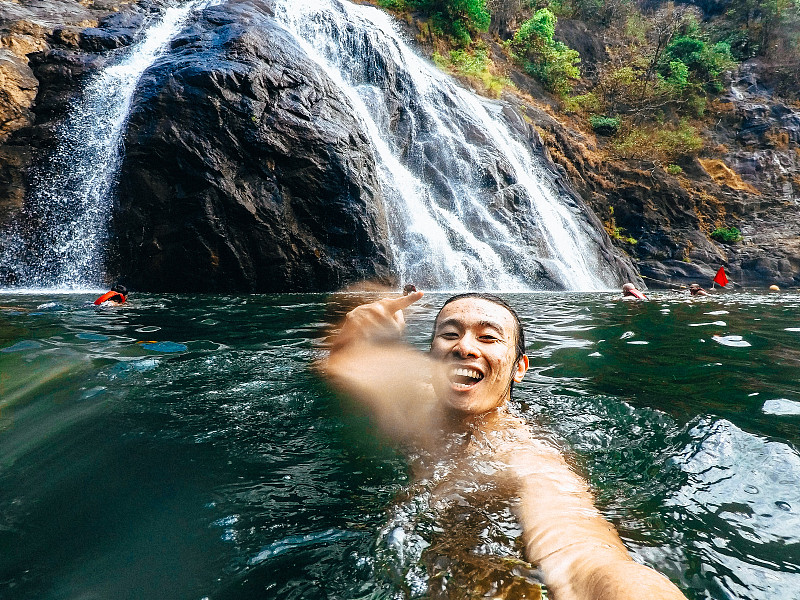 微笑的男人在河里游泳时打手势的肖像图片素材