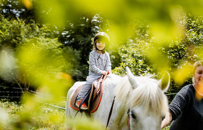 一个年轻女子教一个男孩如何骑马图片素材