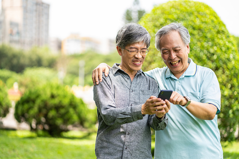 一对台湾父子在公园里玩智能手机图片素材
