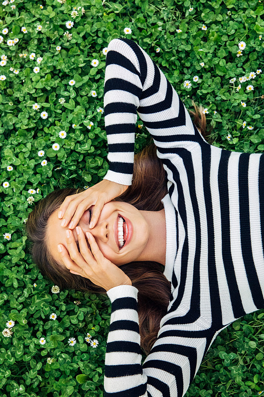 高角度的微笑年轻女子躺在草地上图片下载