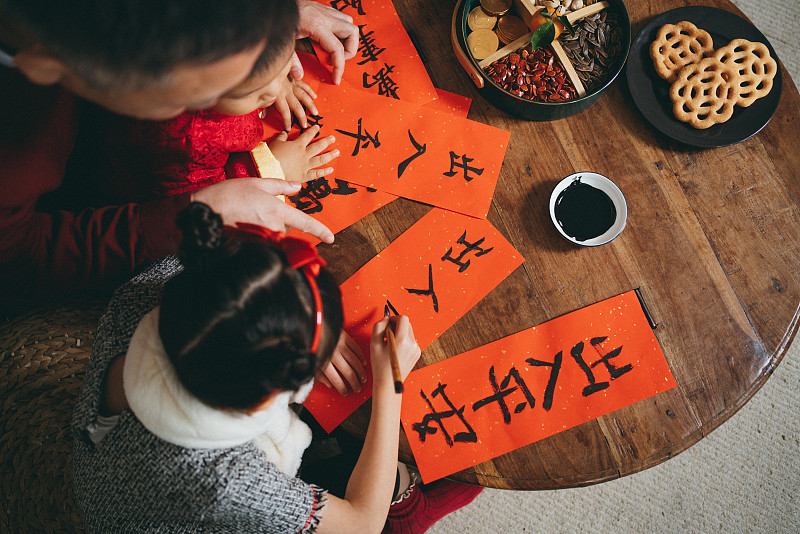 俯视图快乐的小孙女和孙子练习中国书法的中国新年对联与他们的祖父图片下载