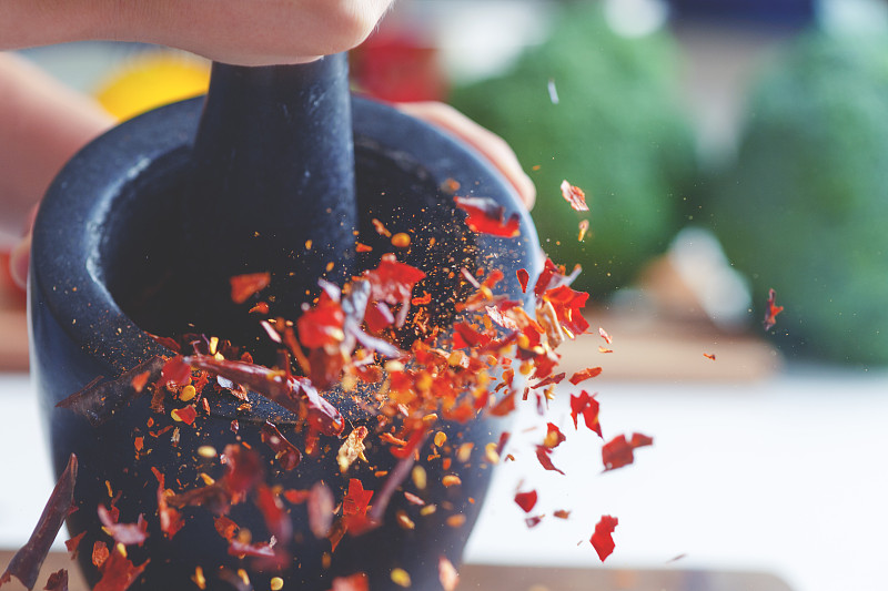 干辣椒被研钵和杵碾碎的动作画面。图片素材