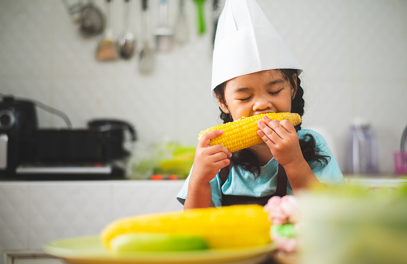 在厨房训练烹饪后，孩子们在休息时间吃玉米图片下载