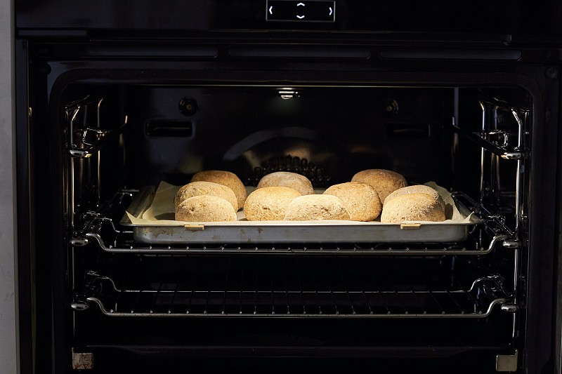 烤箱里烤着家里做的全麦面包卷图片下载