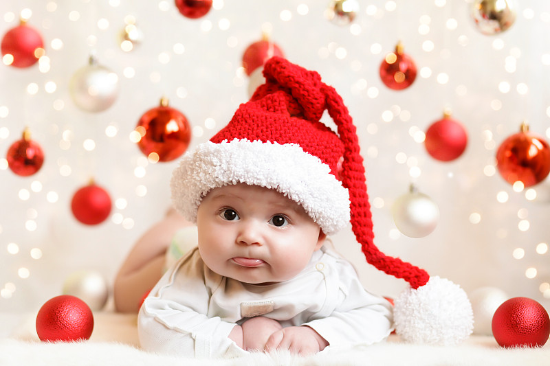 可爱的婴儿在红色的圣诞帽周围的红色球在白色的背景图片下载