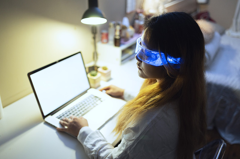 戴着增强现实眼镜在家用笔记本电脑的女人图片下载