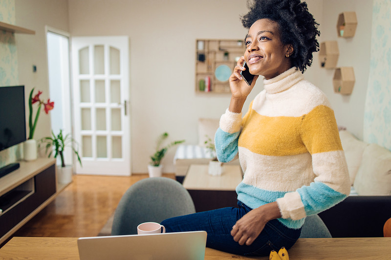 快乐的非裔美国妇女在她的家庭办公室打电话图片下载
