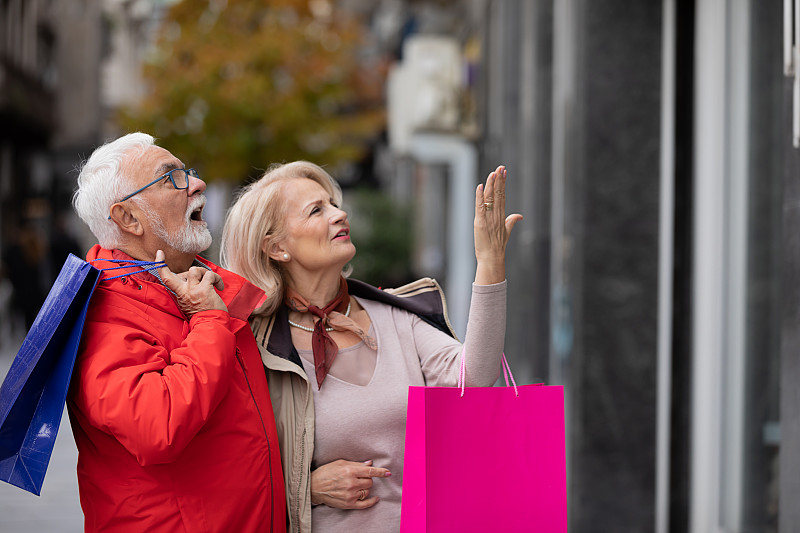 一对快乐的老夫妇走在街上，向购物中心走去。图片下载