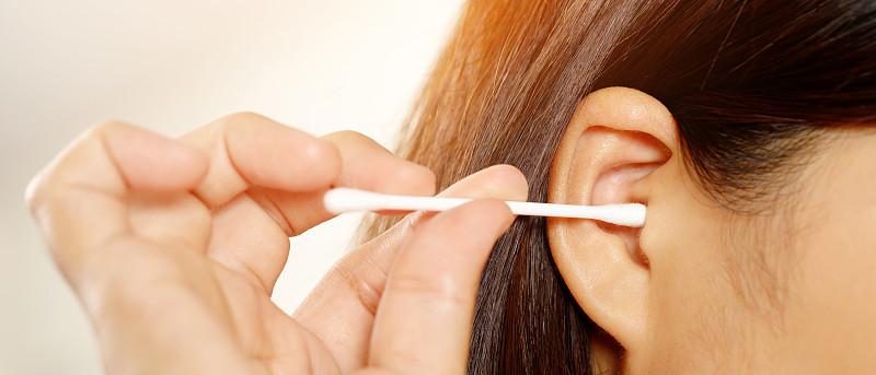 关闭女性清洁耳朵使用棉花棒保健。图片下载