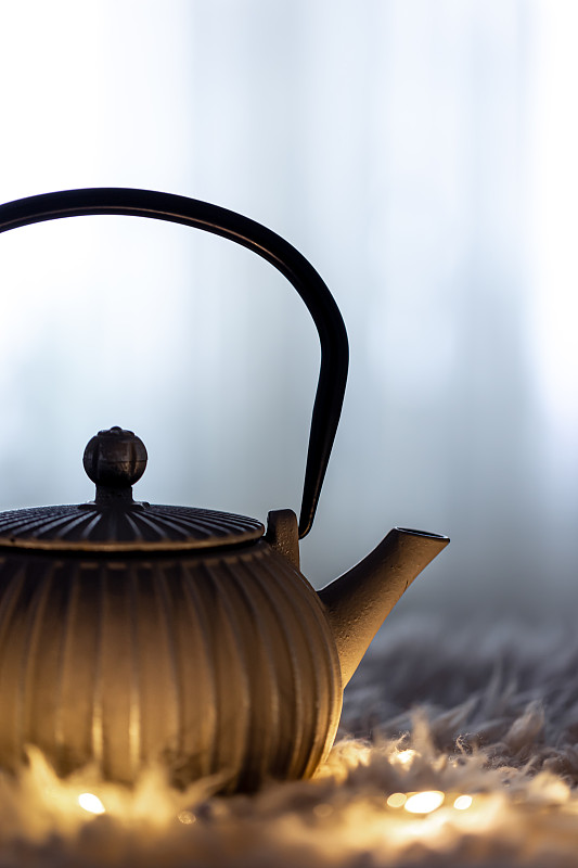 茶壶在黑暗中模糊的背景和花环。图片下载