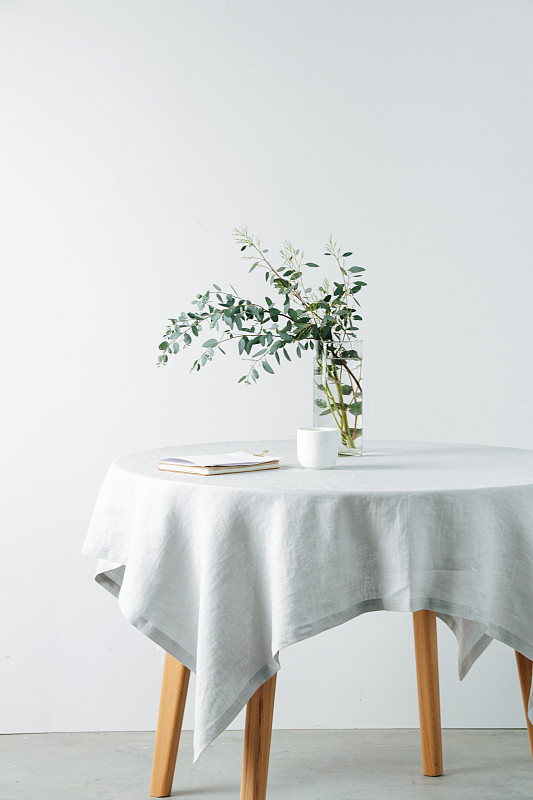 侧视图圆桌与一个粗糙的白色桌布和树枝在一个罐子图片下载