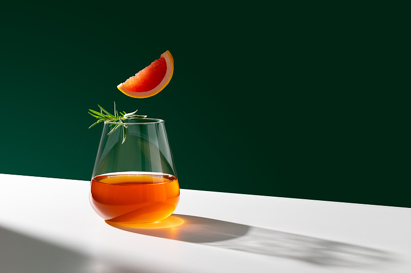 一杯新鲜的尼格罗尼鸡尾酒，配上橙片，点缀上迷迭香。副本的空间。图片素材
