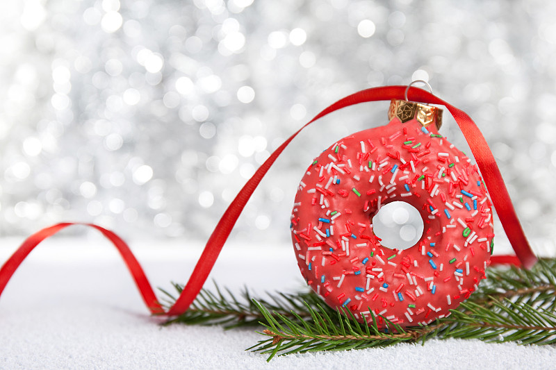 圣诞小玩意装饰制成的粉红色甜甜圈在银色背景与灯图片下载